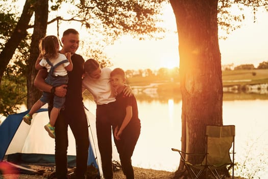 Evening time. Family of mother, father and kids is on the camping.