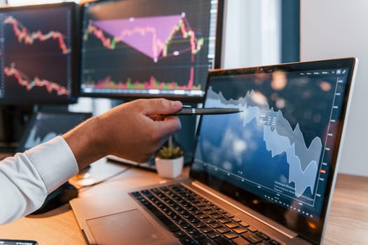 Close up view. Young businessman in formal clothes is in office with multiple screens.