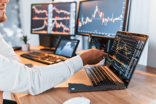 Analyzing information. Young businessman in formal clothes is in office with multiple screens.