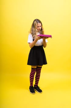 Little teenager girl with pencil case on a yellow background