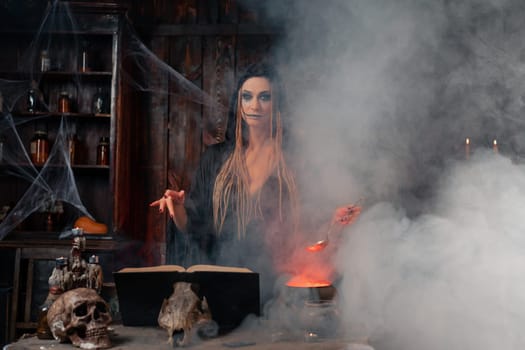 Halloween, witch use magic book and cauldron prepare poison or love potion. Black magic occult female wizard in dark room cage spider web human skull. Necromancer cooking magic potion. voodoo magic