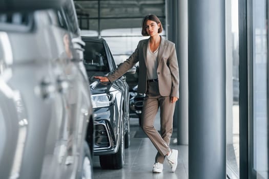 Modern technology. Woman is indoors near brand new automobile indoors.