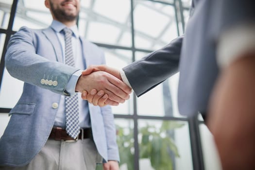 Two diverse professional business men executive leaders shaking hands at office meeting.