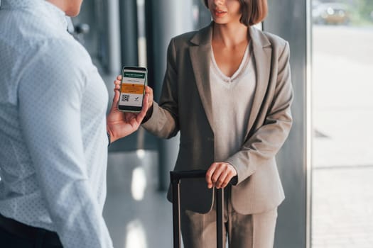Modern technologies. Woman showing her vaccine passport by using smartphone to the man.