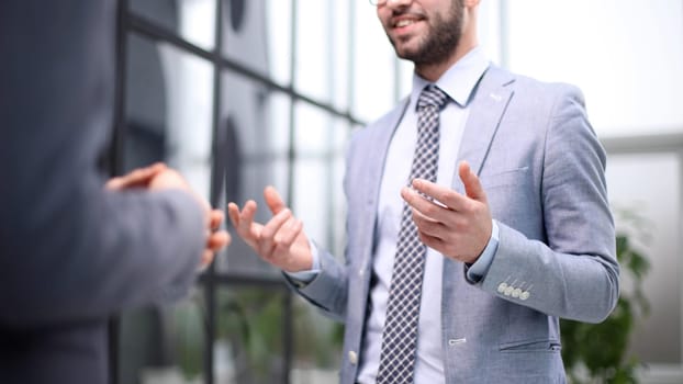 Two Businessmen Having Informal Meeting In Modern Office
