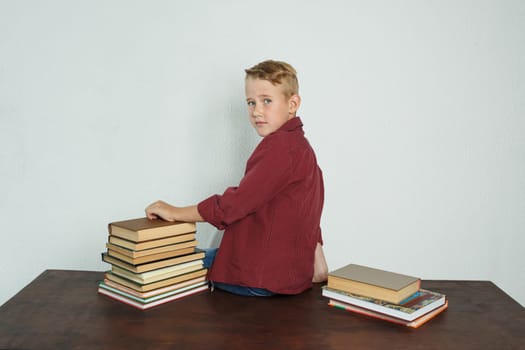 Education concept. A student boy sits on a table with his back to the camera, turned his head to the camera looking at her.