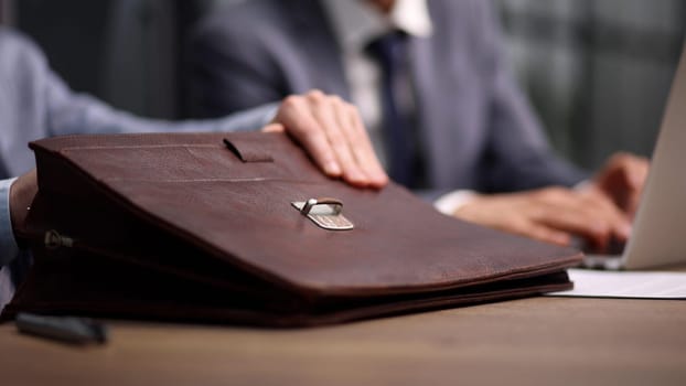 Close-up of a businessman holding a briefcase while sitting at a table