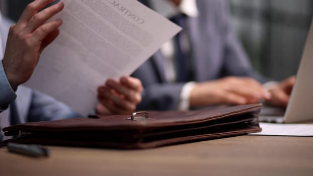 Close-up of businessman holding hands on contract while sitting at table