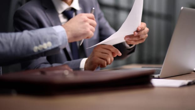 Close-up of businessman holding hands on contract while sitting at table