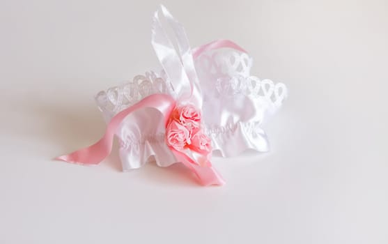 The bride's garter on a pink background. Wedding dress detail.