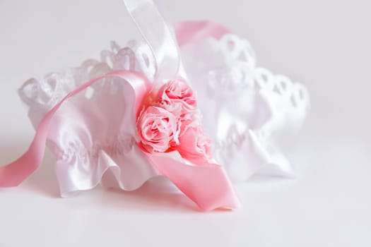 The bride's garter on a pink background. Wedding dress detail.