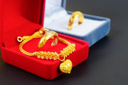 Gold necklace and heart shape pendant with ring on red velvet box.