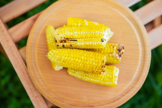 Delicious, sweet young grilled popcorn lies on a wooden board, outdoor recreation, proper nutrition