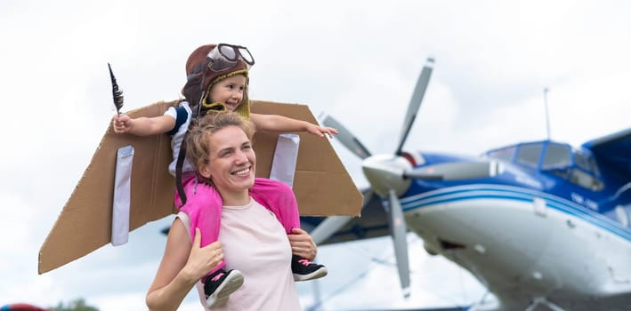 A loving Caucasian woman is playing with her daughter in airplanes at the airfield. A little girl dreams of becoming a pilot sitting in her mother's arms