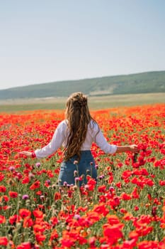Happy woman in a poppy field in a white shirt and denim skirt with a wreath of poppies in her hand posing and enjoying the poppy field