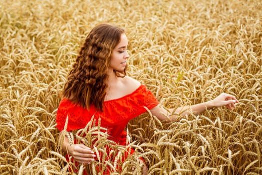 Style redhead girl in red dress tay on yellow wheat field Caucasian real girl. Happy woman enjoying freedom. Portrait of a beautiful young woman on a natural natural background.