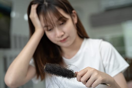 Asian woman have problem with long hair loss attach to comb brush.