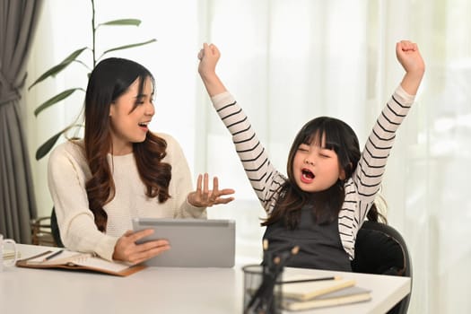 Shot of sleepy little girl yawning and stretching her arms feeling bored or fatigue doing homework.