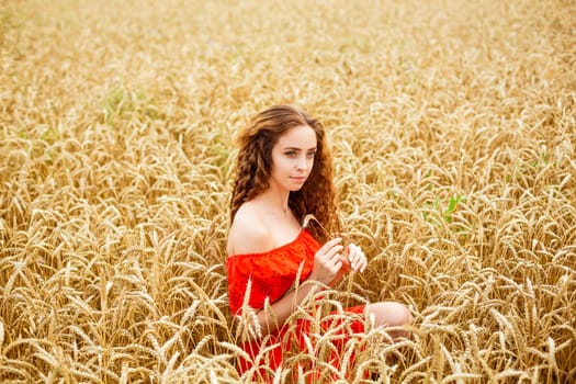 Style redhead lady in red clothe tay on yellow wheat nature Caucasian real girl. Portrait of a beautiful young woman on a natural natural background. Natural cosmetics concept.