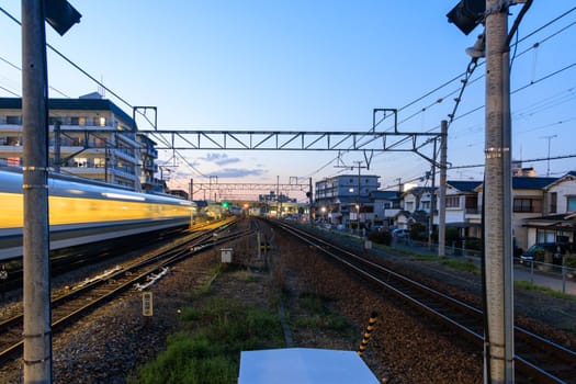 Fast moving train blurs down tracks by homes in residential neighborhood at sunset. High quality photo