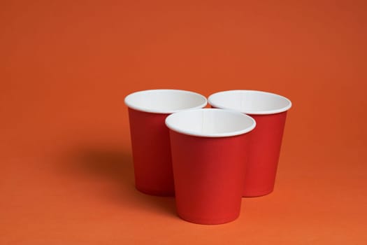 three red paper coffee cups on a brown background with a place to copy the text. Morning concept.