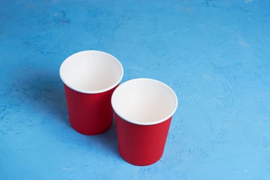 Two red paper coffee cups on a blue background. Morning concept.