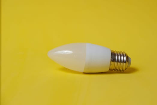 White LED light bulb candle on a yellow background. High quality photo