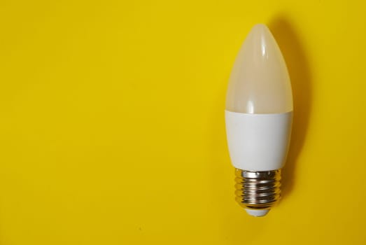 White LED light bulb candle on a yellow background. High quality photo