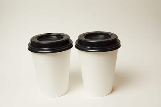 Paper coffee container with black lid and coffee beans on a white background white coffee paper cup with black lid takeaway coffee