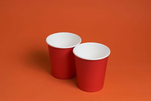 Two red paper coffee cups on a brown background with a place to copy the text. Morning concept.