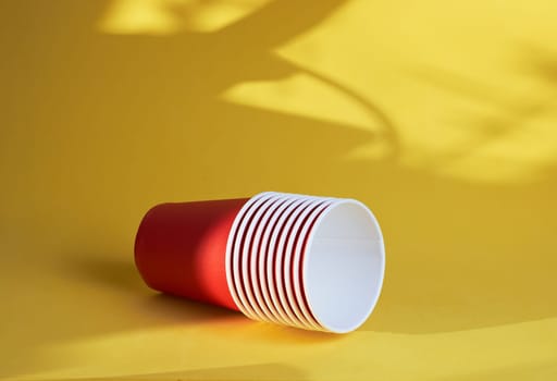 red paper coffee cups on a yellow background are the morning concept of disposable tableware