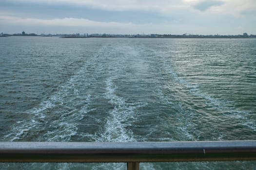 the flowing water seen from the deck of a cruise ship with Den Helder in the background