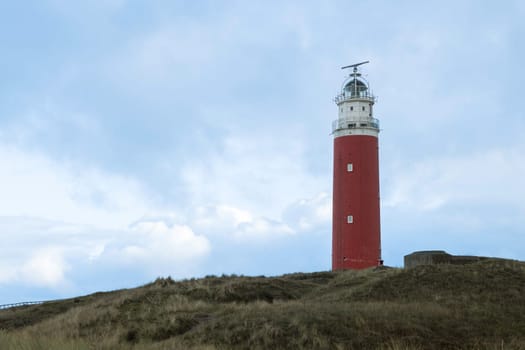 Red lighthouse at the little isle of Texel, the Netherlands with dunes as background
