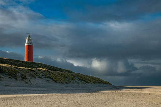 Red lighthouse at the little isle of Texel, the Netherlands with dark rainy clouds as background
