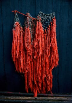 orange fishing nets hang on a dark wooden background
