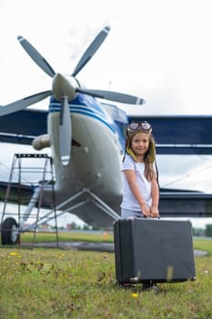 A cute little girl playing on the field by private jet dreaming of becoming a pilot.