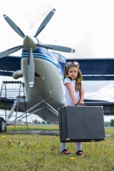 A cute little girl playing on the field by private jet dreaming of becoming a pilot.