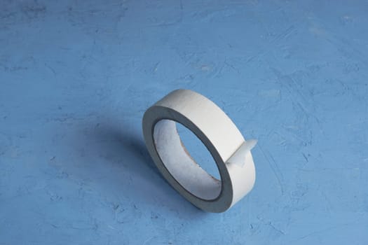 Extreme close-up image of a roll of adhesive tape on a blue background
