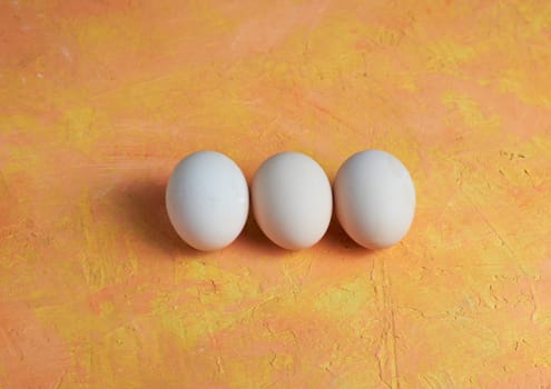 Three red Easter white eggs on a yellow background. Colorful decoration of Easter eggs. Flat position, top view. with a place to copy the text. Minimal idea for an Easter concept