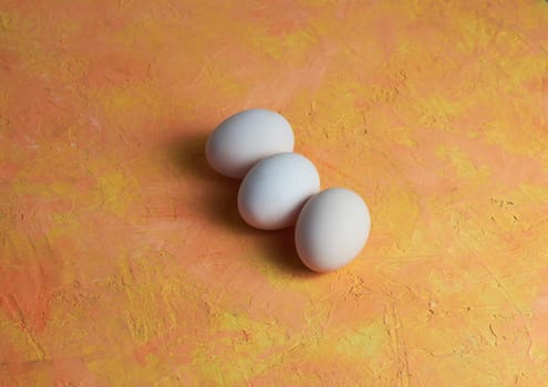 Three red Easter white eggs on a yellow background. Colorful decoration of Easter eggs. Flat position, top view. with a place to copy the text. Minimal idea for an Easter concept