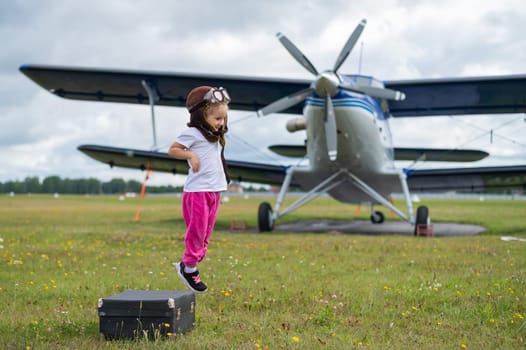 A cute little girl playing on the field by a four-seater private jet dreaming of becoming a pilot.