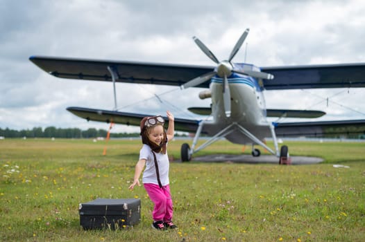 A cute little girl playing on the field by a four-seater private jet dreaming of becoming a pilot.