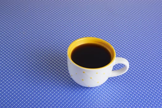 Flat lay view of dark hot coffee cup on blue background with copy space