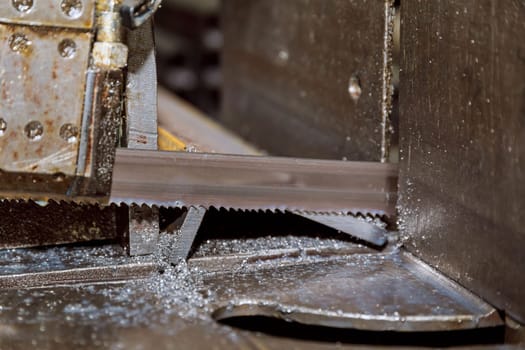 Cutting steel profiles and pipes on a band saw in production.