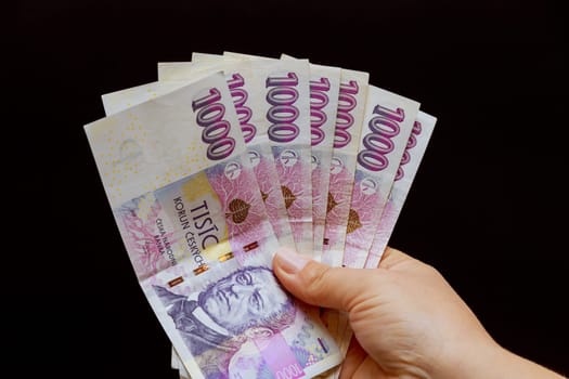 Woman lists Czech crowns on a black background. The national currency of the Czech Republic. Banknotes of one thousand krowns each.