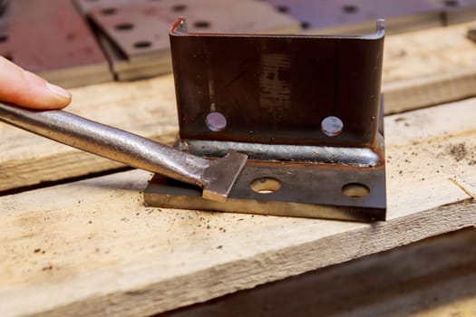 The worker cleans the welding seam with the help of a special home-made tool from balls formed during welding.