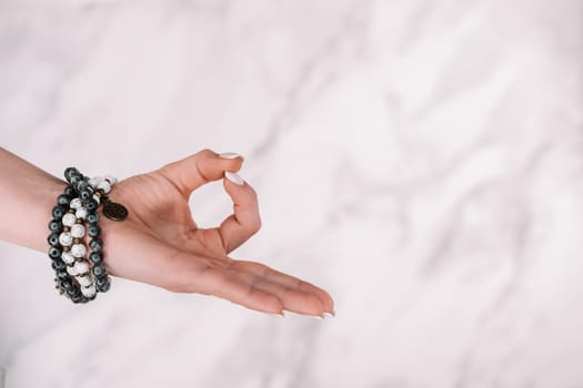 Jnana Gian mudra - Om on white background. Female hand with mala beads bracelet. Woman meditating, doing yoga