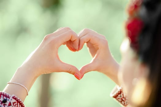 Ukrainian woman in traditional embroidery vyshyvanka dress making sign of shape heart. Ukraine, volunteering, donation help and love concept.