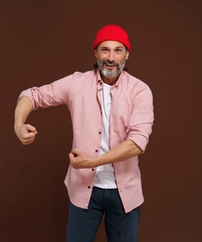 Mature handsome concept. Show strength. middle-aged European man with gray beard showcases his physical strength by flexing his biceps and clenching his fists, exuding confidence and determination. High quality photo