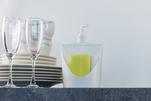 Clean dishes with dishwashing gel and yellow sponges on the kitchen table. copy space